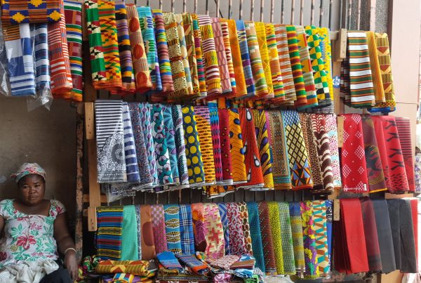 A trader with kente cloth on display at Makola Market, Accra