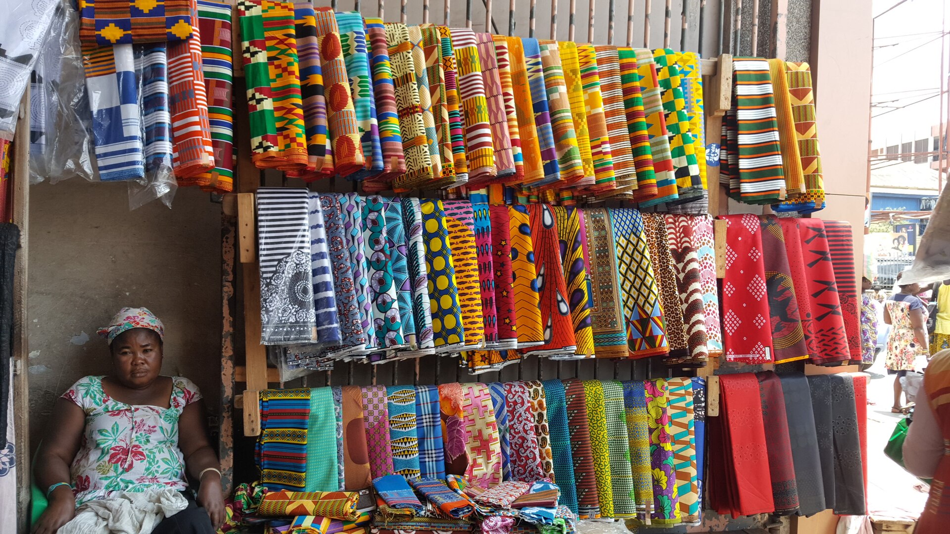 A trader with kente cloth on display at Makola Market, Accra